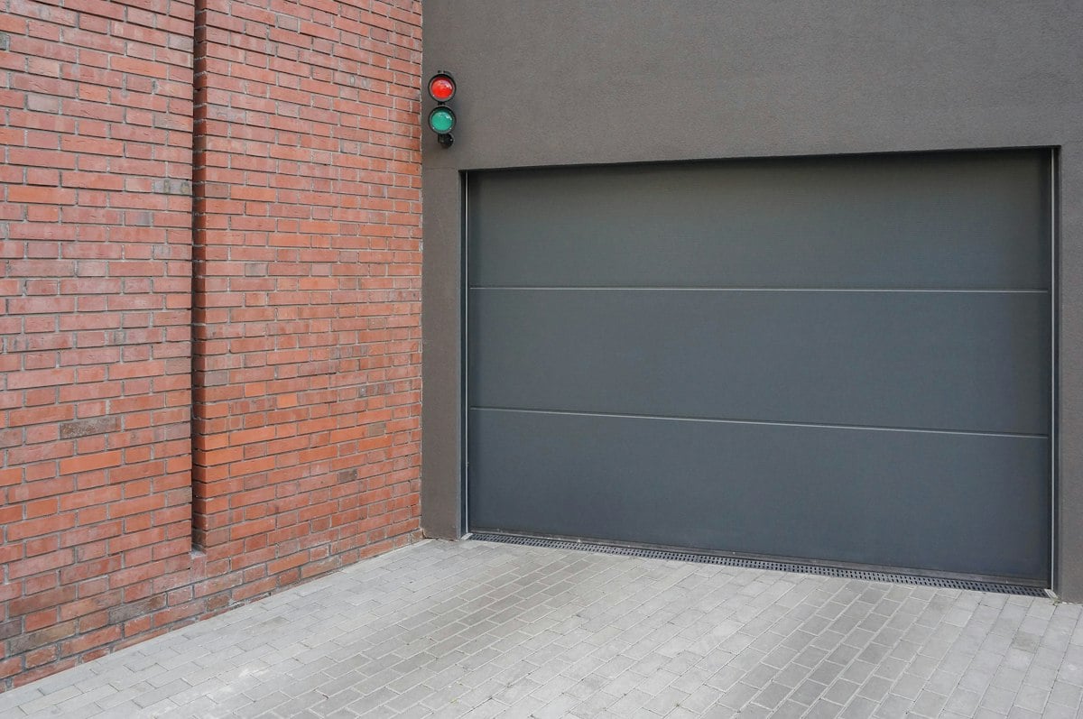 Gray sectional door beside a brick wall