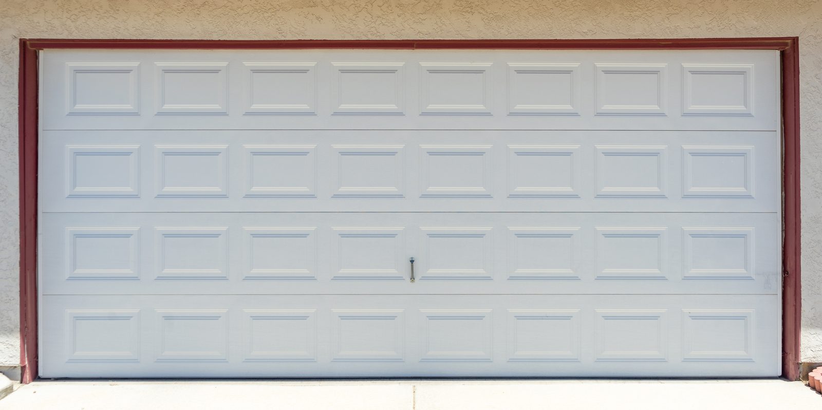 Wide white raised-panel garage door on a suburban house